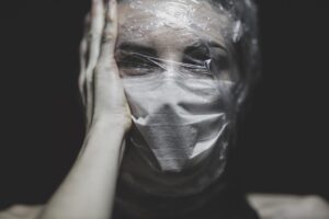 a depressed woman with a nose mask on and a plastic wrap on her face 