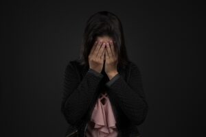 a sad lady sitting down and covering her face - What Is Bipolar Depression? 